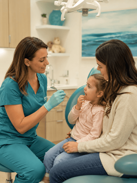 Pediatric dentist discussing tongue and lip tie concerns with a child and parent